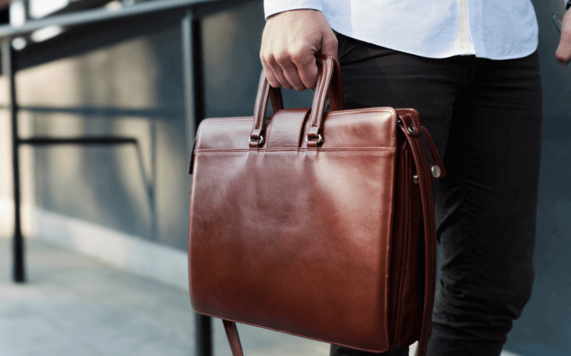 Image of a man with a leather briefcase. Focus on the briefcase.