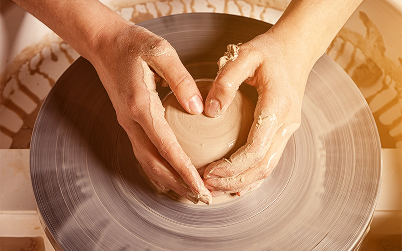 A small image of a pair of hands shaping clay on a pottery