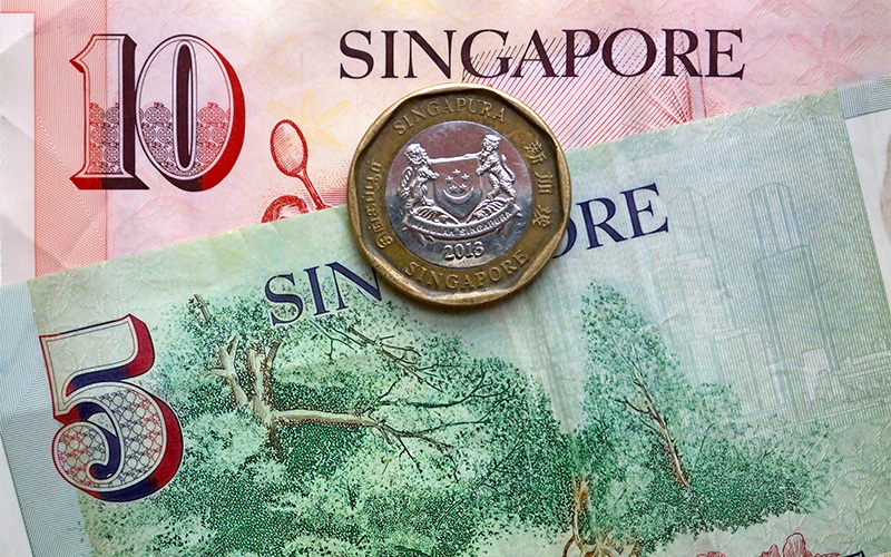 Close-up of Singapore currency featuring a $10 note, a $5 note, and a $1 coin