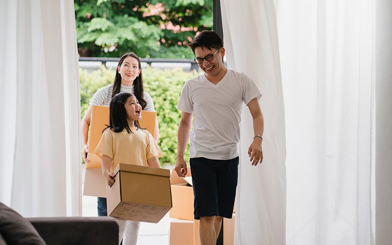 Happy family carrying cardboard boxes while moving into a new home